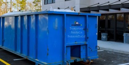 Blue roofing dumpster in front of building.