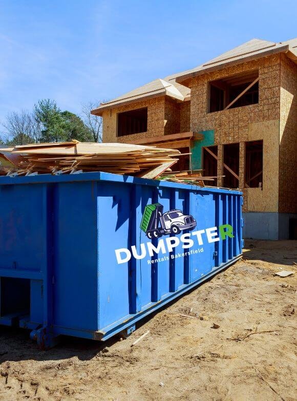 A house under construction with a dumpster located in front, indicating ongoing renovation activities.