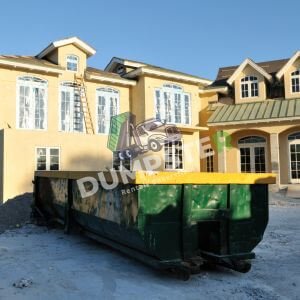 A dumpster placed in front of a residential house, indicating ongoing renovations or clean-up activities.